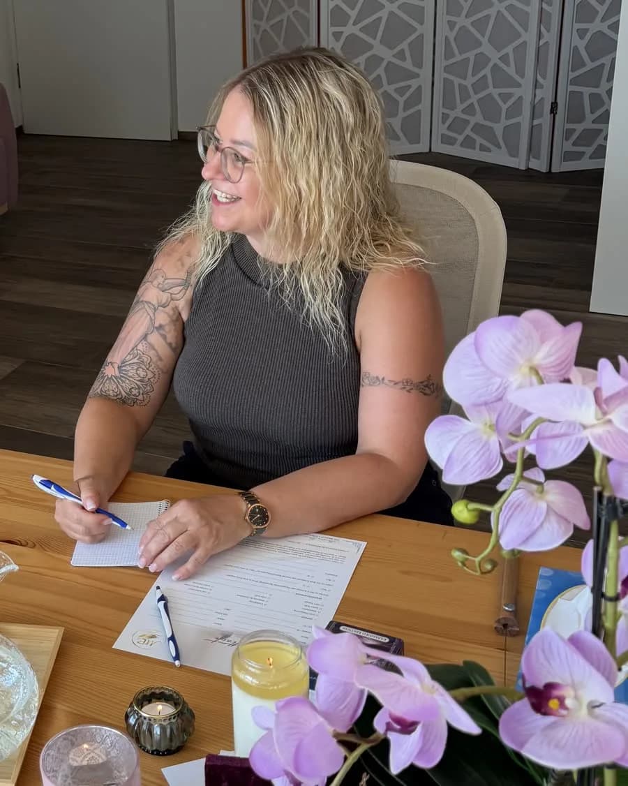 Mariana Bauer sitzt lächelnd an einem Tisch und macht sich Notizen.